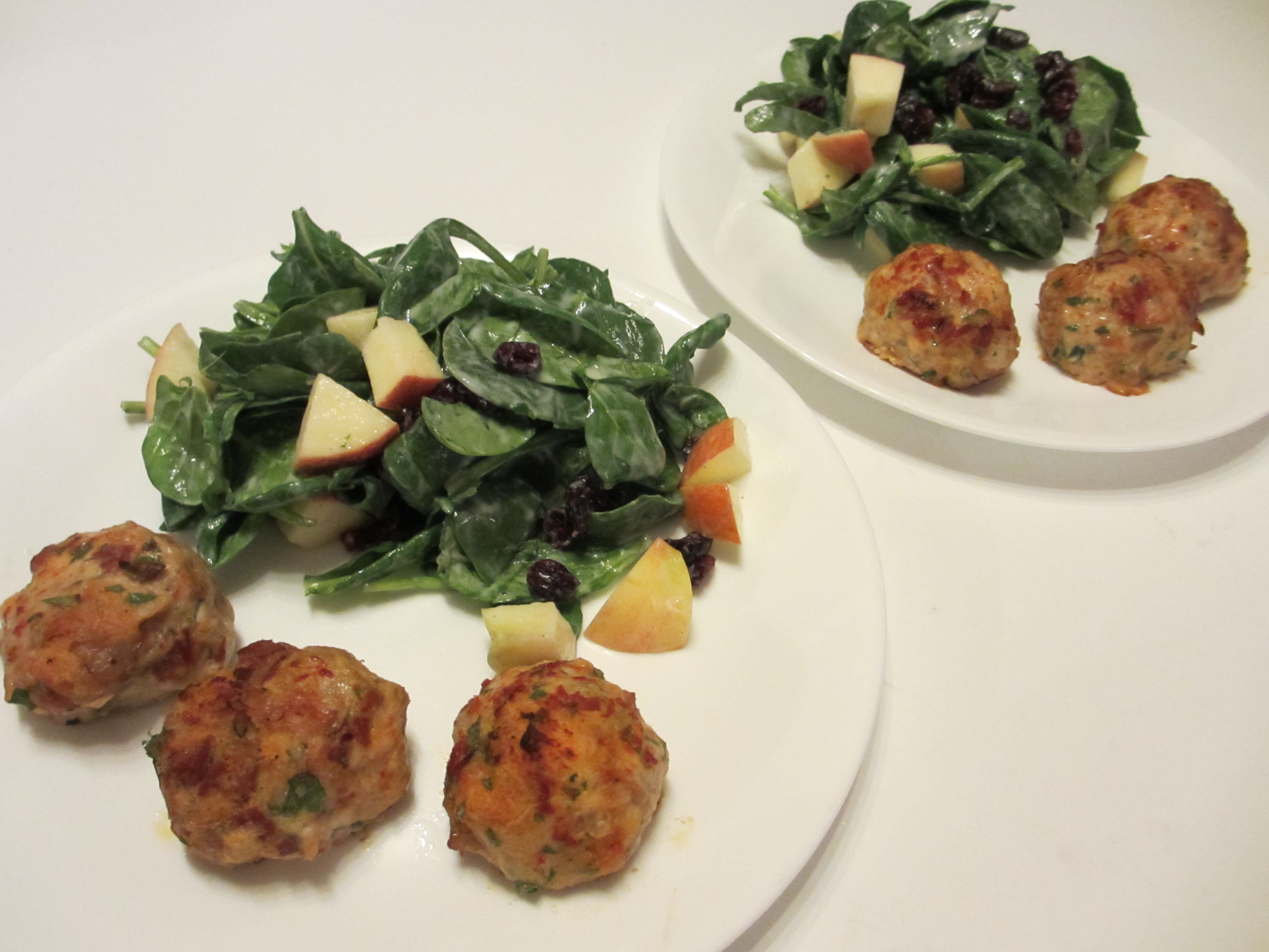 Plated chicken meatballs with a fresh spinach and apple salad.