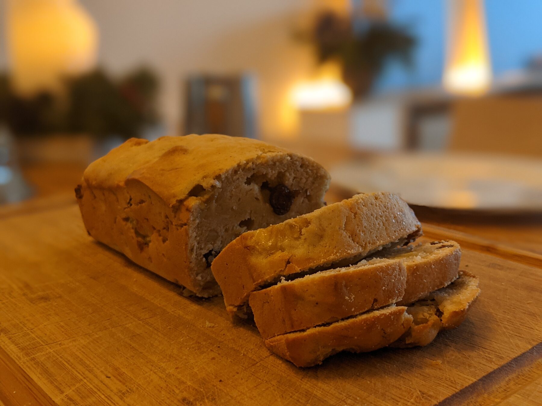 Banana bread sliced on a wooden board in a warmly lit kitchen.