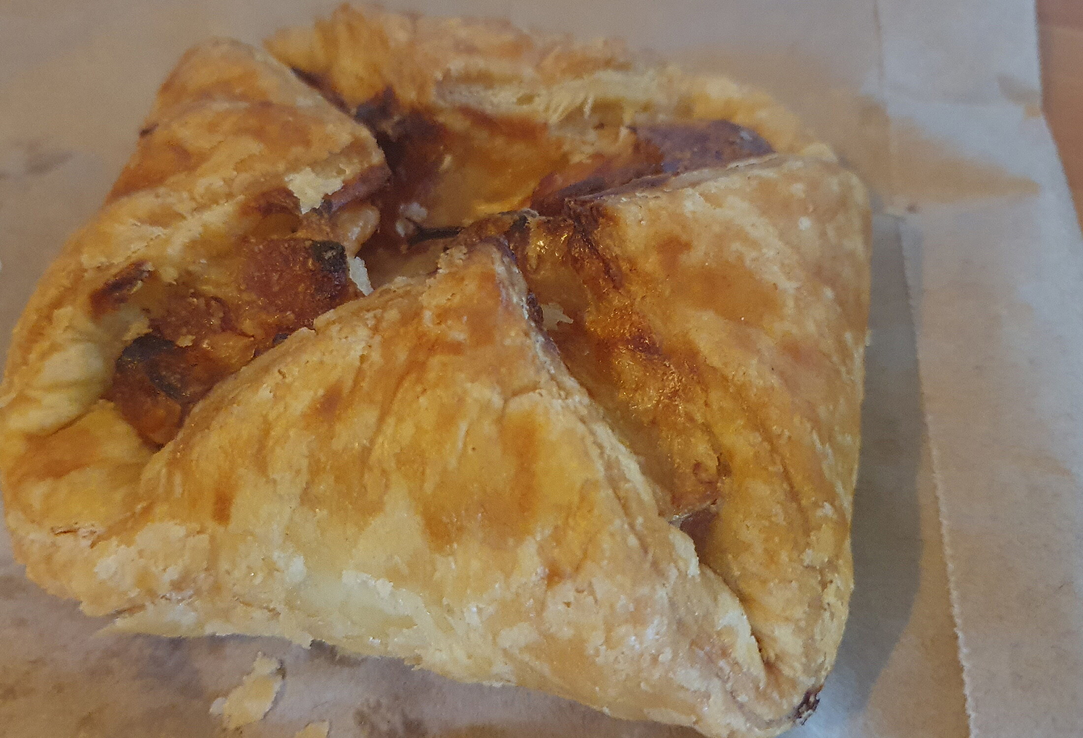 A golden ham and cheese puff pastry folded into a square pocket on parchment.