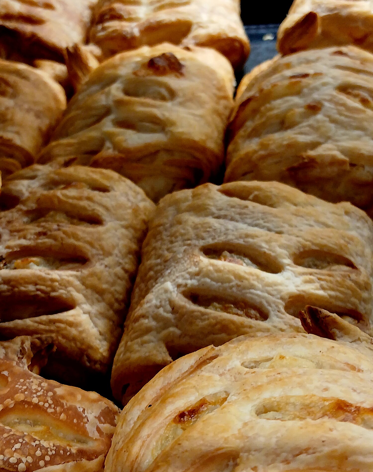 Several baked puff pastries filled with ham and cheese arranged close together.