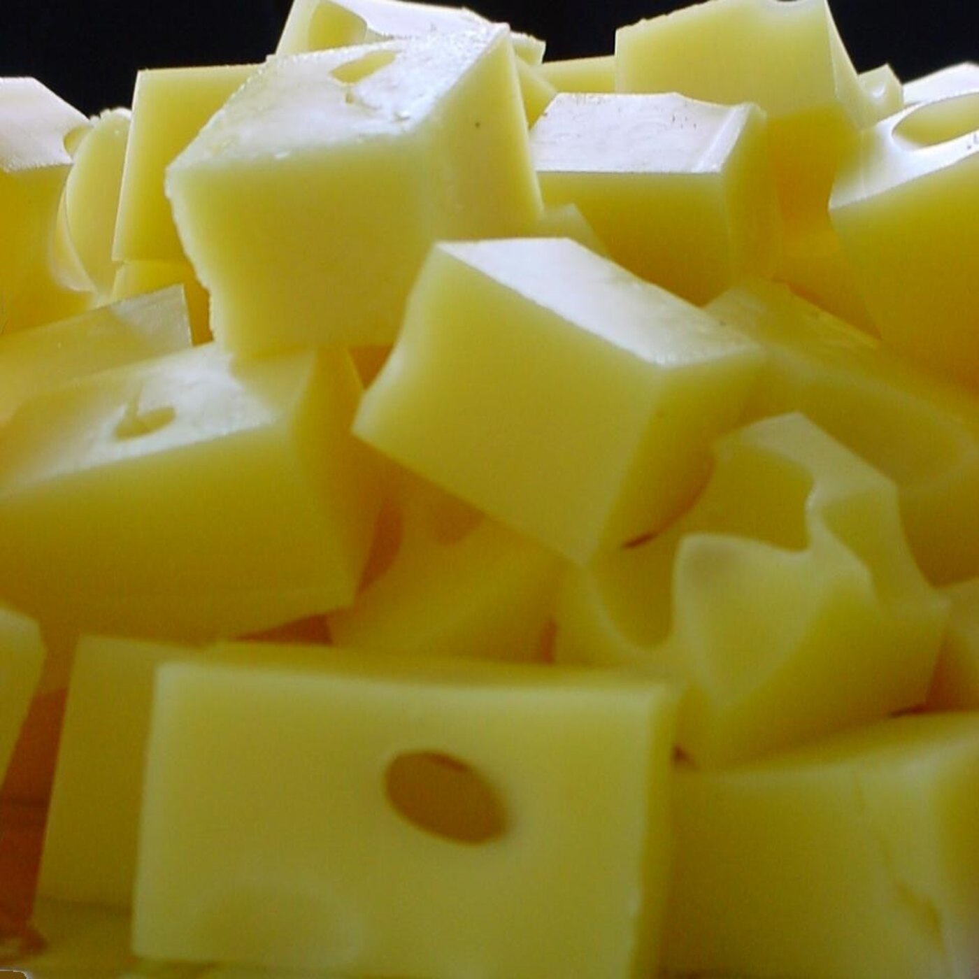 Close-up of pale Swiss cheese cubes with round holes.