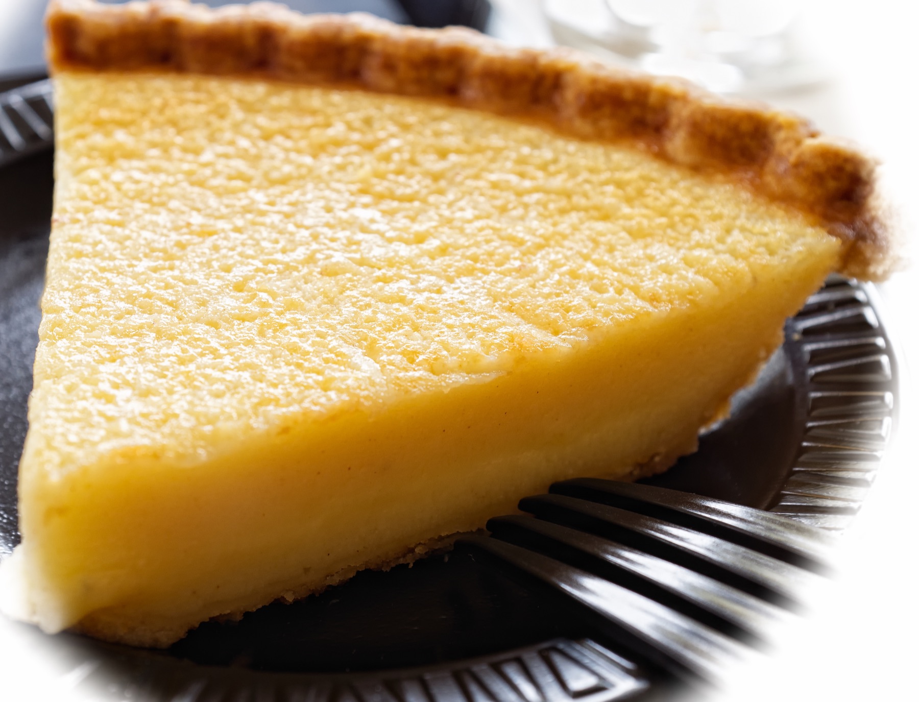 A golden buttermilk pie cooling in a metal pie plate.
