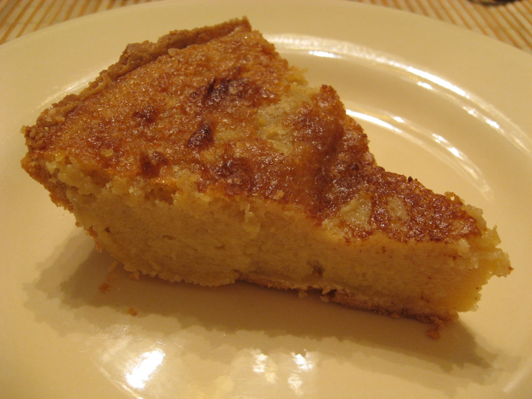 A slice of buttermilk chess pie on a plate beside the remaining pie.